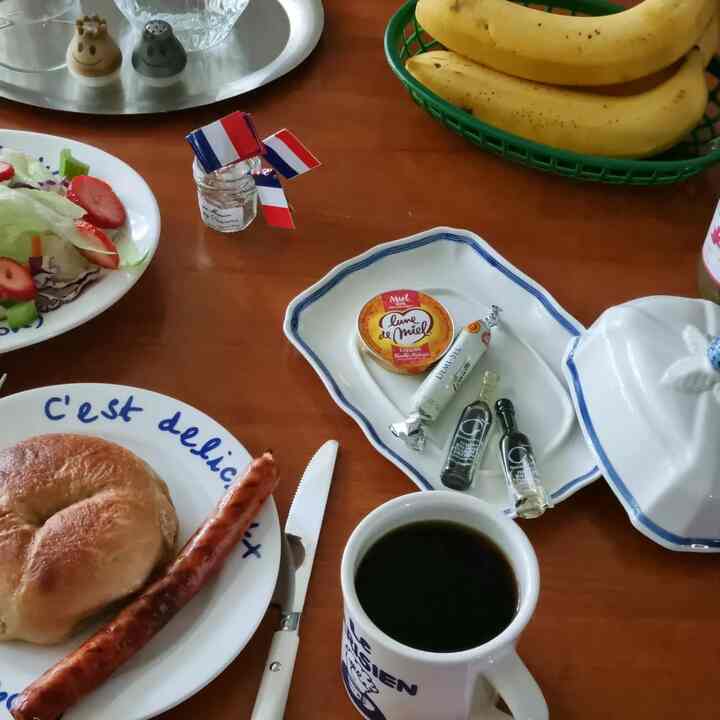 温かみのある茶色の木製ダイニングテーブルに白い皿やマグカップ、バナナのバスケットが置かれた雰囲気のあるおうちカフェ