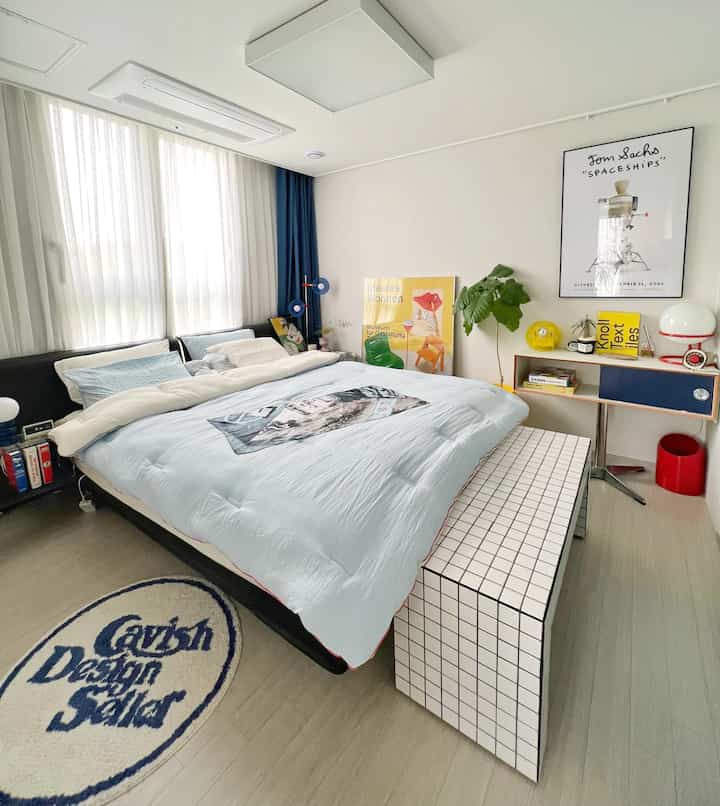 パステルブルーのトーンが特徴の寝室、大きなベッドとモダンな家具が明るく清潔な雰囲気を作り出しています。