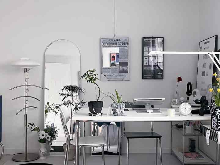 ホワイトとシルバーのミニマルなホームオフィス、植物と照明が配置された清潔感のある作業空間