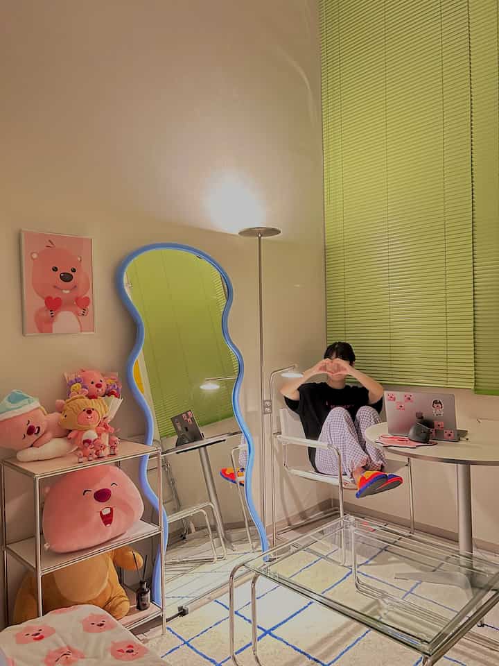 Modern living room for single household featuring lime green blinds and blue wavy mirror as color accents