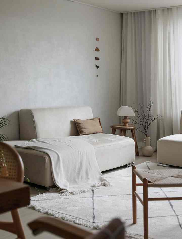 明るいベージュとホワイトトーンのリビング、ファブリックソファと木製の小物が自然な雰囲気を演出するインテリア