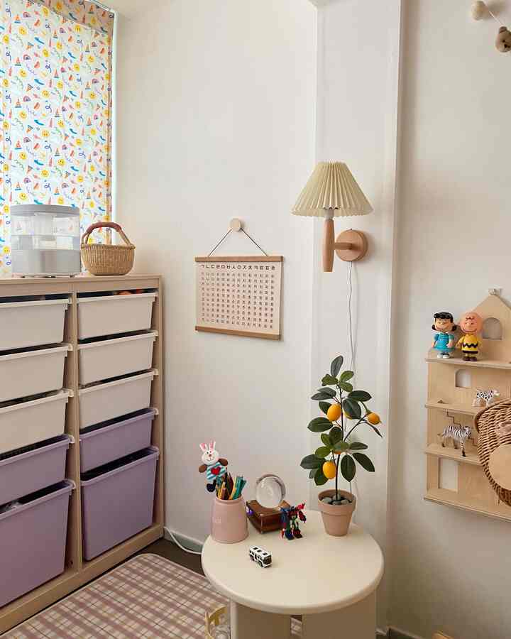 Beige-toned natural kids' room featuring multicolored storage bins, a round table with artificial lemon tree, and cozy wooden elements