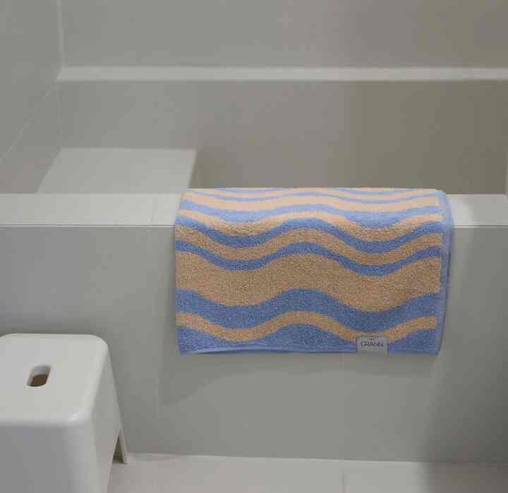 Modern bathroom space with white and beige striped towel hanging, featuring a clean and minimal atmosphere