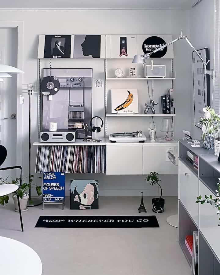 Modern minimal living room with white walls and shelves, featuring a black rug and a curated record display area