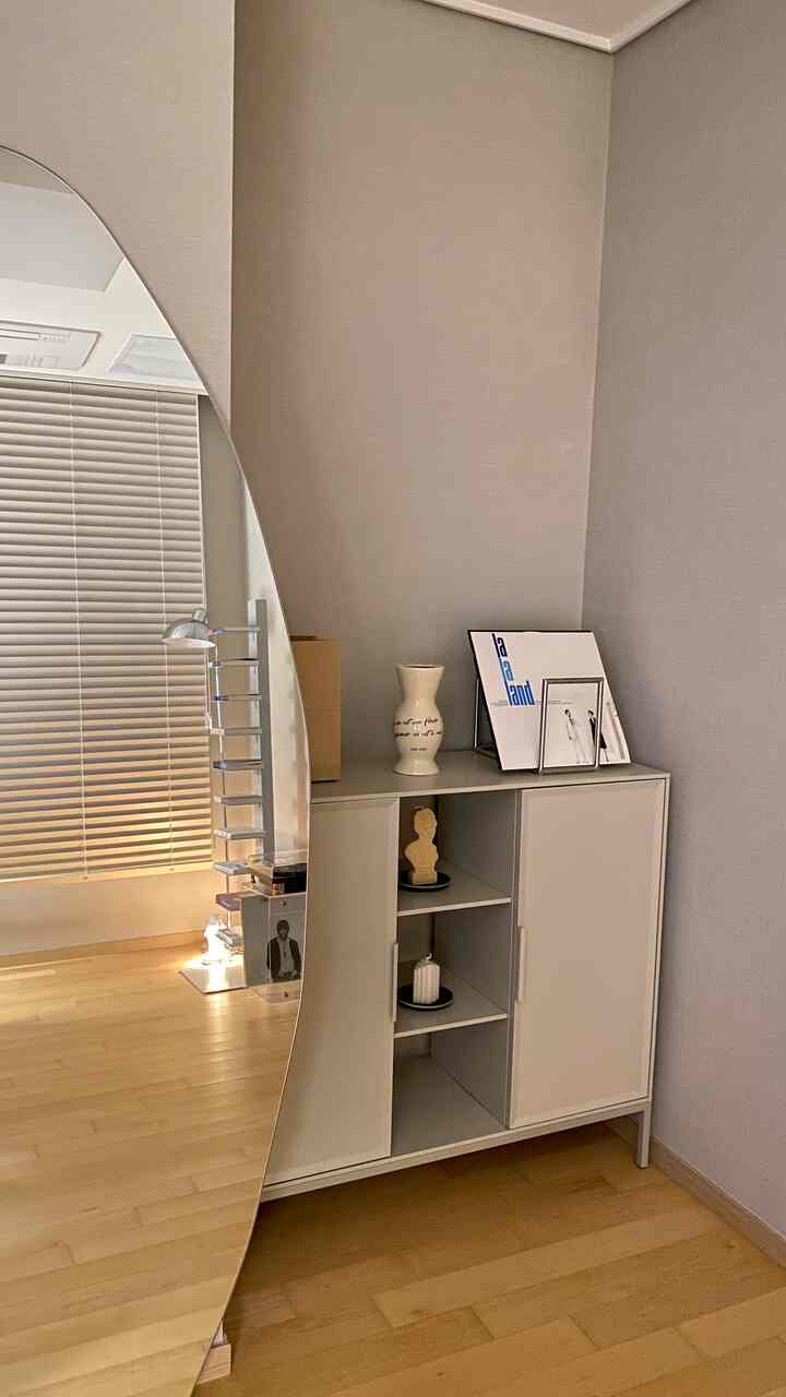 Modern study space in white and wood tones featuring a large mirror and storage cabinet with mid-century modern elements