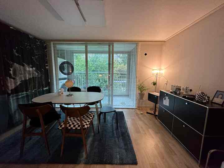 ナチュラルカラーと木目調が調和したリビング、ホワイトブラインドとダイニングテーブルが配置された落ち着いた雰囲気の空間