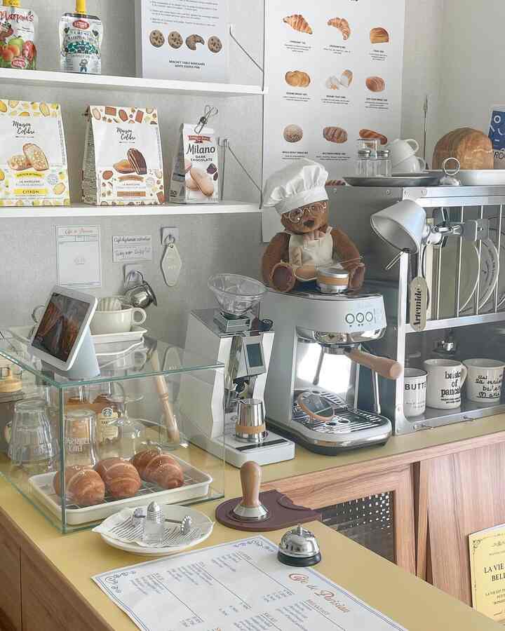 Beige and white toned studio home cafe featuring coffee machine, grinder, bakery shelves with cozy atmosphere