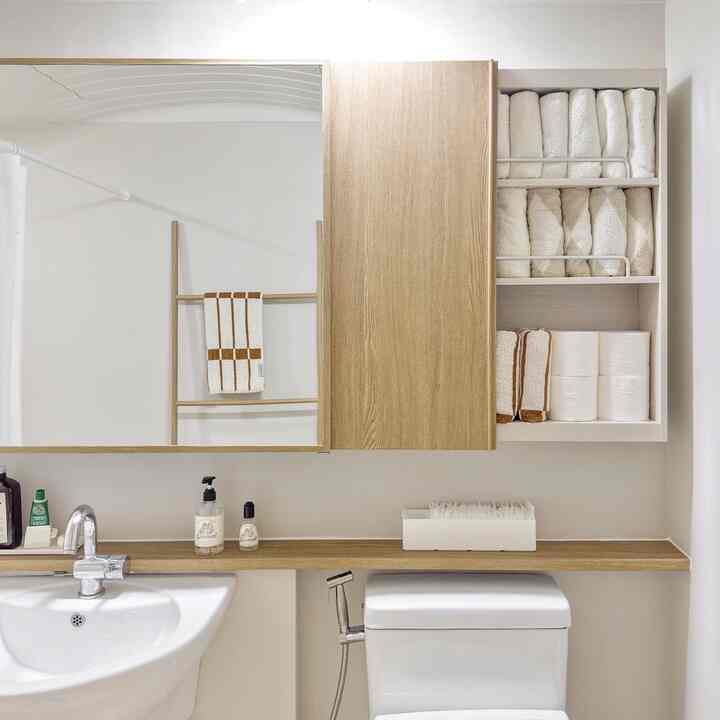 White and natural wood tone bathroom featuring organized storage and towels in a modern setting