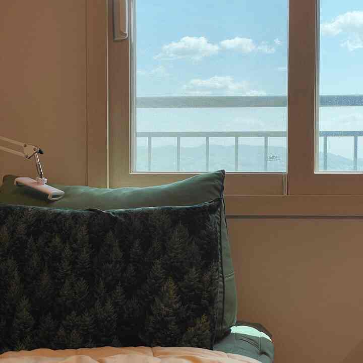 Calm bedroom space with green pillows and bedding featuring veranda window with natural light