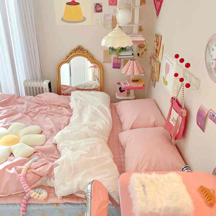 柔らかなピンクと白の色調のかわいらしい寝室、ベッドとクッション、装飾的な金色の鏡が配置された雰囲気のあるインテリア