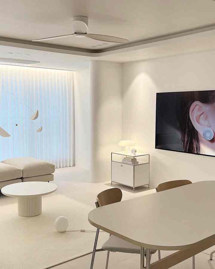 Soft white-toned living room featuring a modern round tea table and wooden chairs with a bright, simple mood