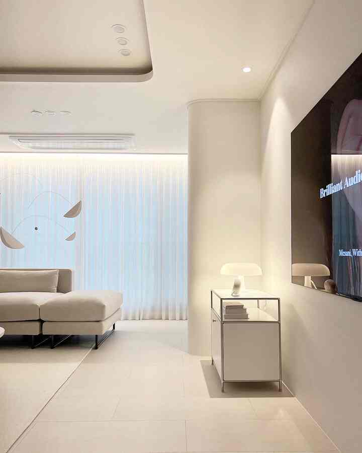 White-toned living room featuring a beige sofa and TV with a modern and clean atmosphere