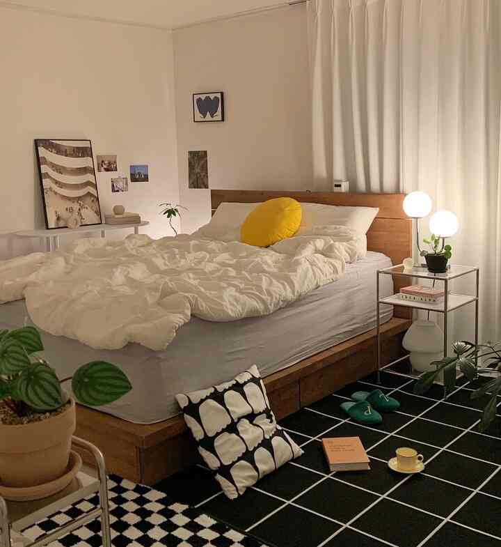 A cozy bedroom featuring white and wood tones, modern bed framed by a black patterned carpet as a focal point