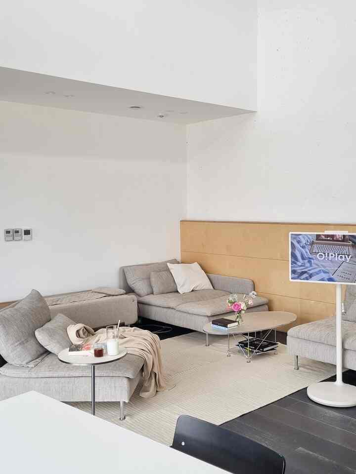 A white and gray toned modern mid-century living room featuring sectional sofas, a coffee table, and side table in a cozy setting