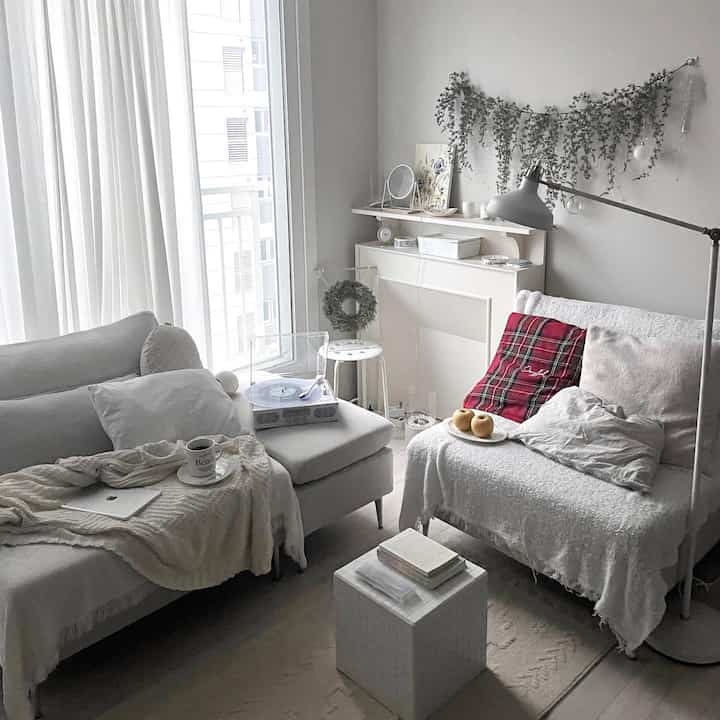 ホワイトトーンの横長リビングルーム、2つのソファとターンテーブル、クリスマスガーランドが配置された雰囲気のある空間