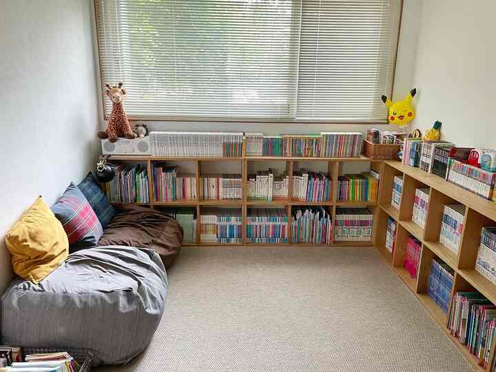 Natural color toned kids' room featuring large bookshelves, a soft sofa, and window blinds creating a cozy atmosphere