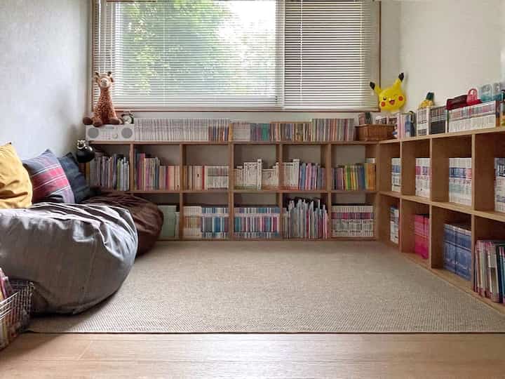 ナチュラルな色調と木目調の子供部屋、大きなラグと本棚、柔らかいソファが配置された雰囲気のある読書と遊びの空間