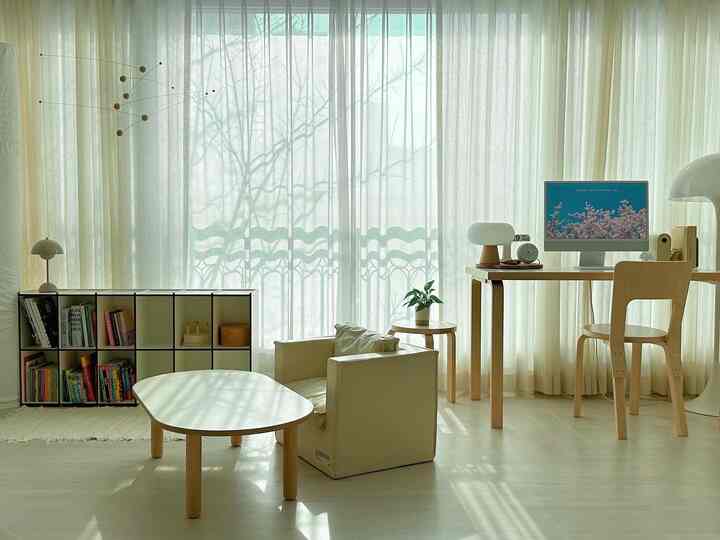 Bright home office living room with beige curtains and natural wood tone furniture
