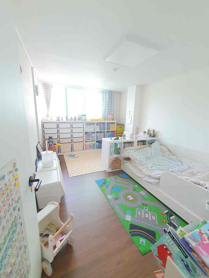 Bright white and brown toned kids' room featuring bookshelves and toy storage with cozy natural play and sleeping zones