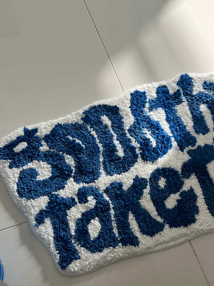 A refreshing bathroom space with a blue text-design rug placed on a white tiled floor