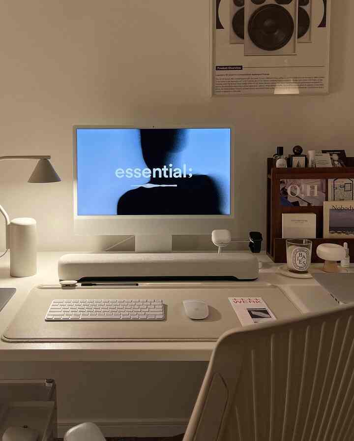White and beige toned home office featuring a simple modern desk with iMac, keyboard, and mouse arranged neatly