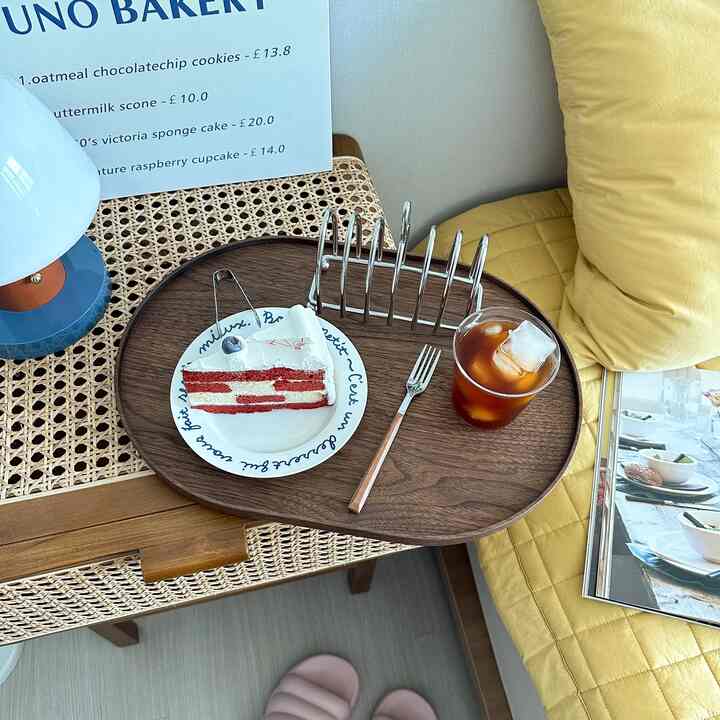 Yellow-toned bedroom space featuring rattan table with wooden tray holding cake and iced coffee for a cozy home cafe vibe