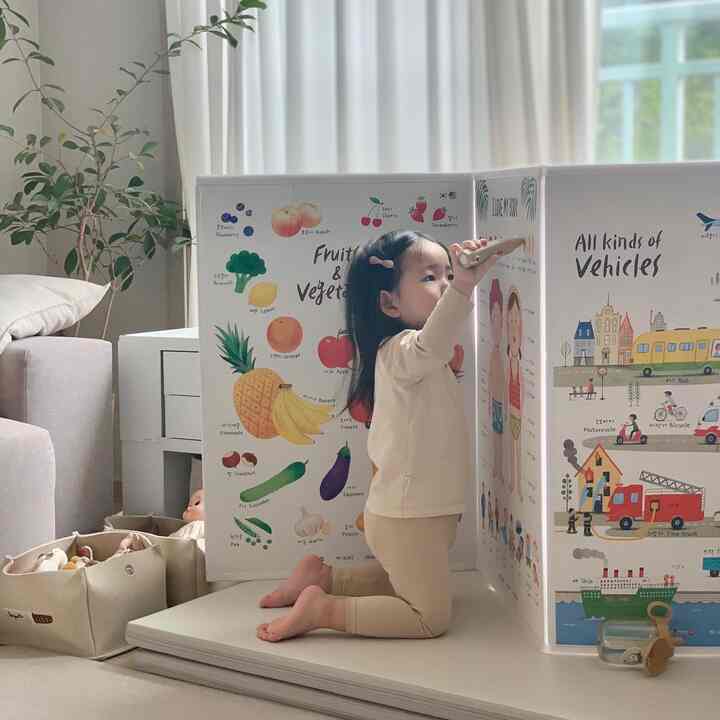 Natural toned kids' room featuring a child playing in front of an educational folding poster, creating a warm atmosphere