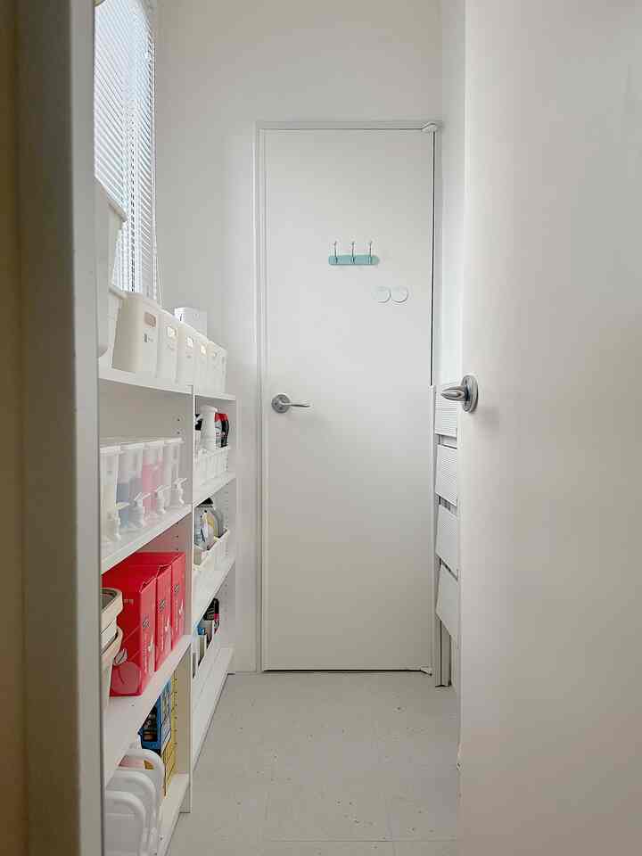 Bright white-toned utility passage with neatly arranged storage cabinet on the left, creating a clean and functional space