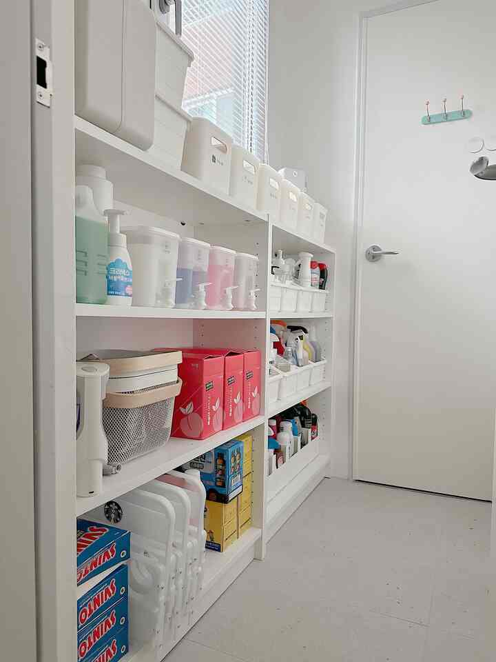 White-toned narrow pantry space featuring neat white cabinets and various storage containers arranged orderly