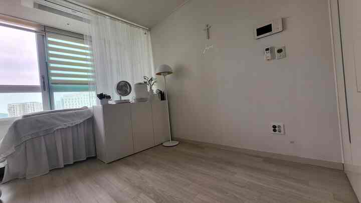 Bright white-toned studio apartment featuring a storage cabinet and mushroom floor lamp by the window with a clean atmosphere