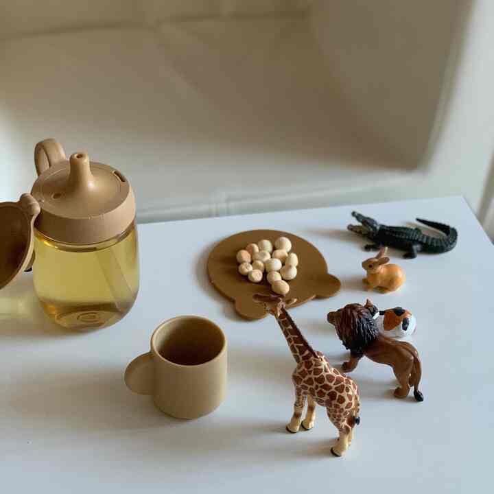 ベージュ調の子供空間、おもちゃの動物と赤ちゃん用食器が配置された遊び場