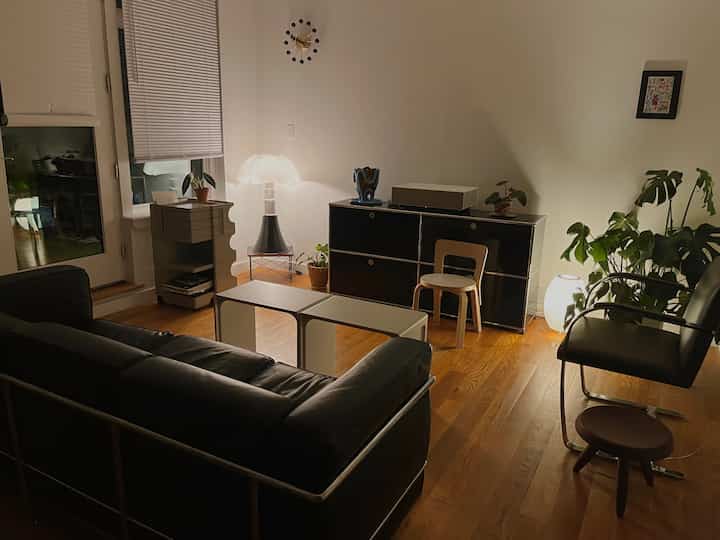 Brooklyn style living room with wood-tone floor and black furniture under warm, dim lighting