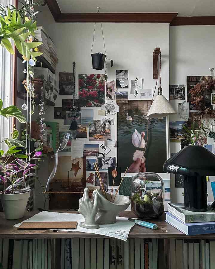 Natural-toned small workspace featuring diverse wall posters and plants creating a cozy atmosphere