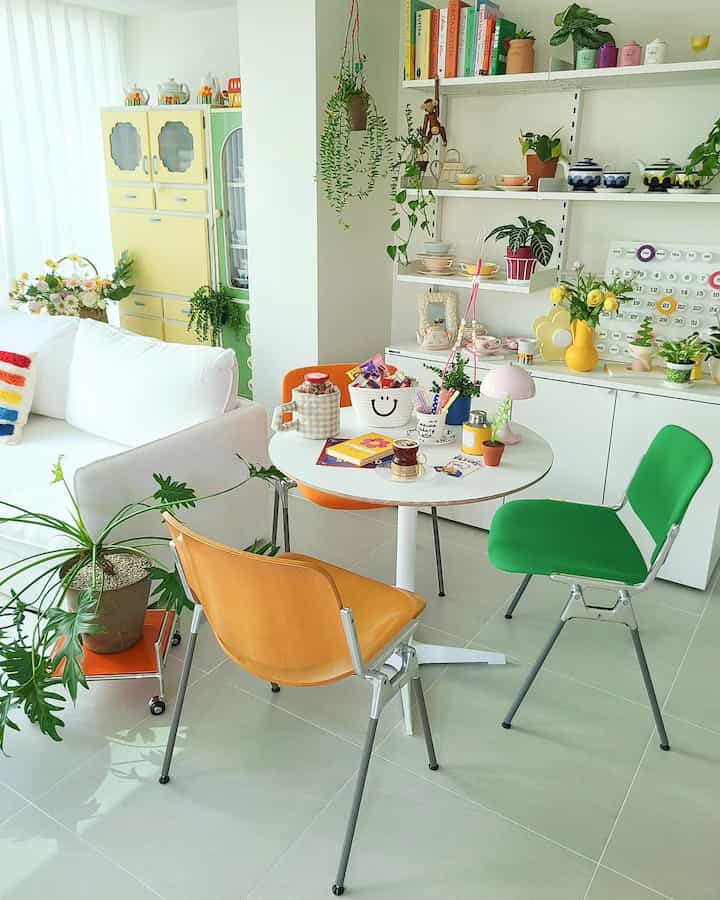 明るく白を基調としたリビング、丸テーブルとヴィンテージチェア、棚には多彩なホームカフェアイテムが配置された温かみのある空間