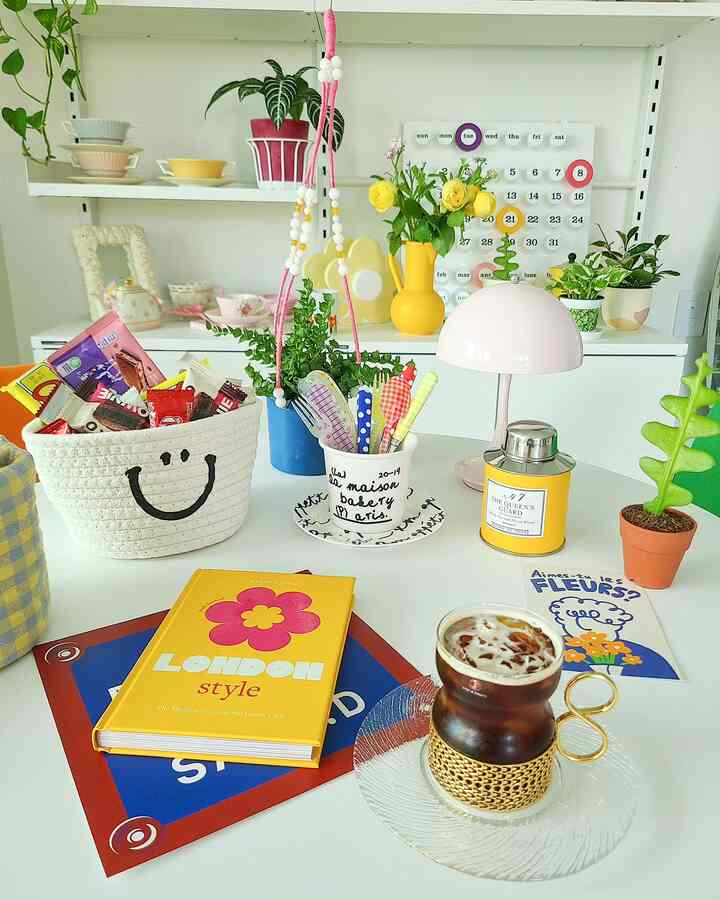 Bright white and yellow toned home cafe space featuring shelves with plants and cups, a table with coffee cup and storage basket.
