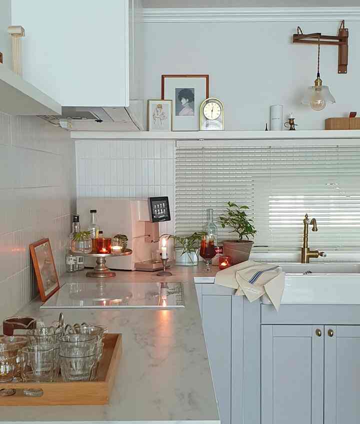 柔らかなホワイトとウッドトーンの落ち着いたキッチン、コーヒーマシンと植物が配置されたナチュラルモダンなインテリア