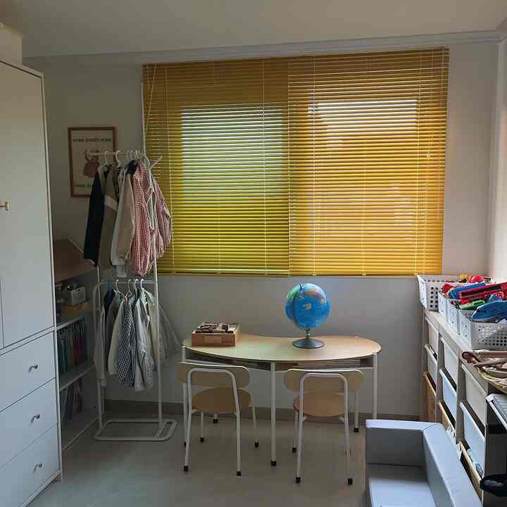 黄色いブラインドがある6畳の子供部屋、ナチュラルなトーンの机と椅子、ハンガーラック、収納バスケットが整然と配置された雰囲気のあるインテリア