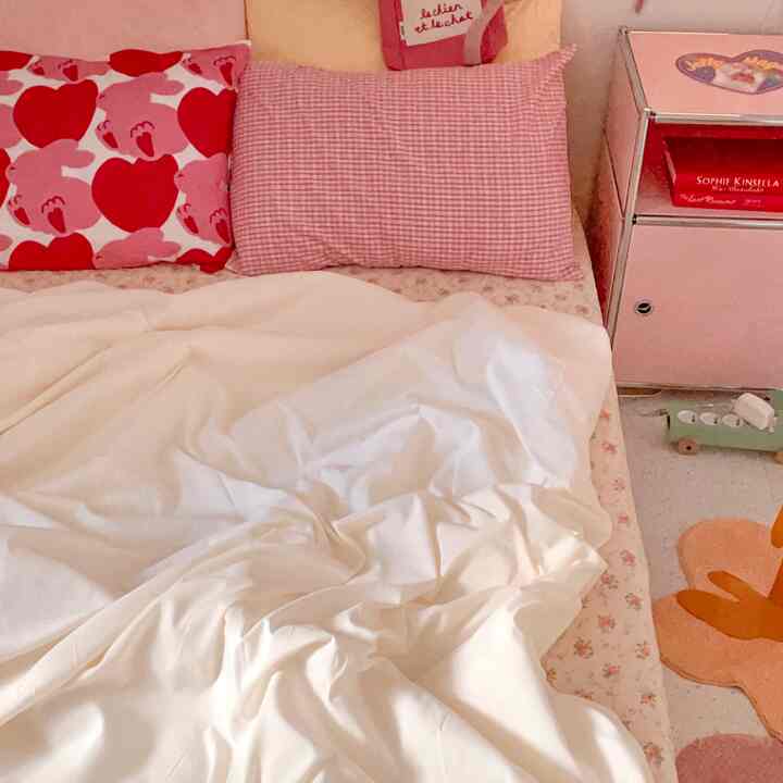 Pink and white toned bedroom space featuring pillows and bedding with warm atmosphere