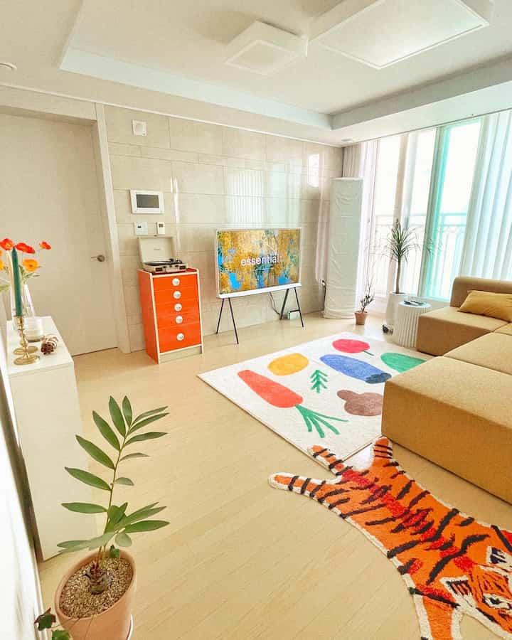 Beige-toned living room featuring a beige sofa, colorful rugs, and a TV stand with a cozy atmosphere
