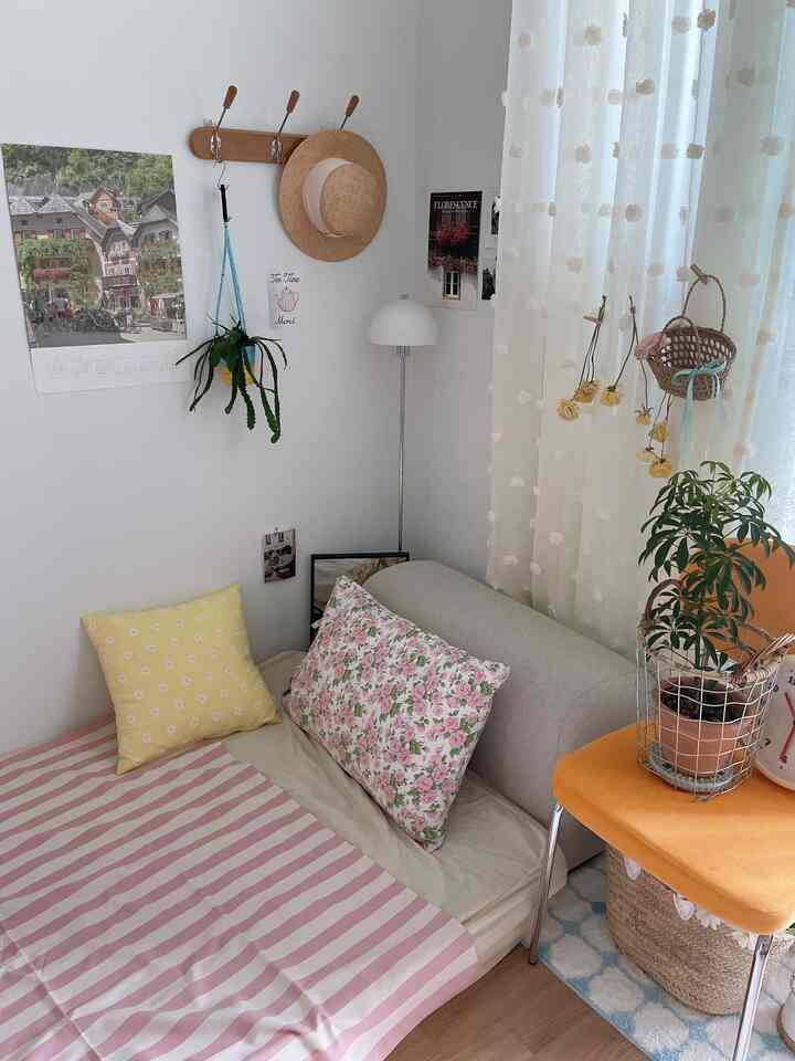 Soft natural-tone bedroom featuring floral cushions and pillows with white pompom curtains, creating a cozy atmosphere
