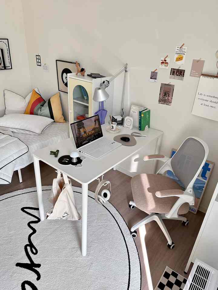 A white and beige toned single household home office featuring a desk, office chair, bed, and minimalist decor in a cozy room