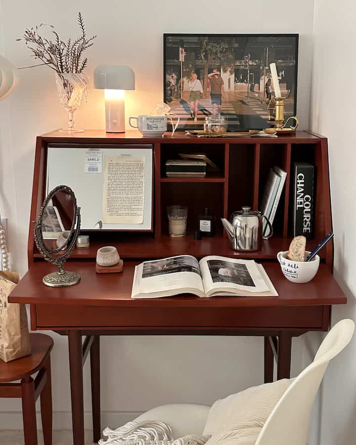 Warm wood-toned home office featuring a desk with shelves, a table lamp, and minimal natural decor creating a cozy simple atmosphere