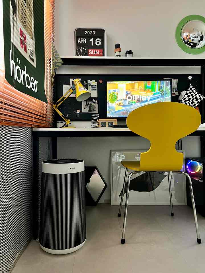 White and black toned home office featuring a desk with a central monitor and a yellow chair creating a cozy workspace