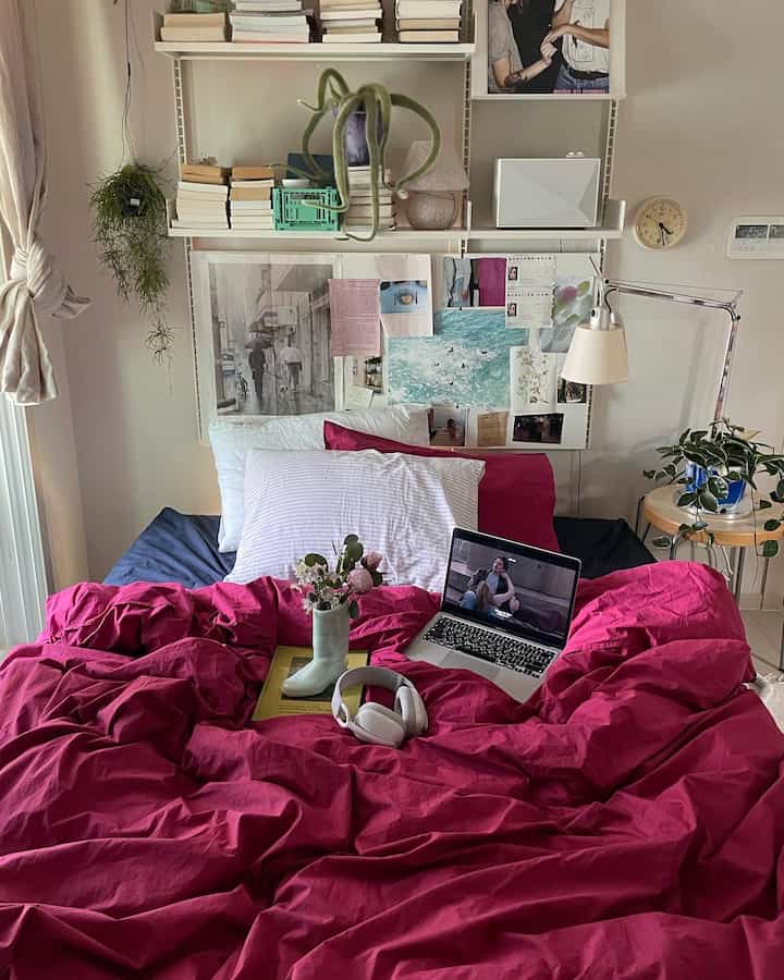 Magenta-toned bedroom with bedding and a laptop placed, creating a cozy and comfortable atmosphere