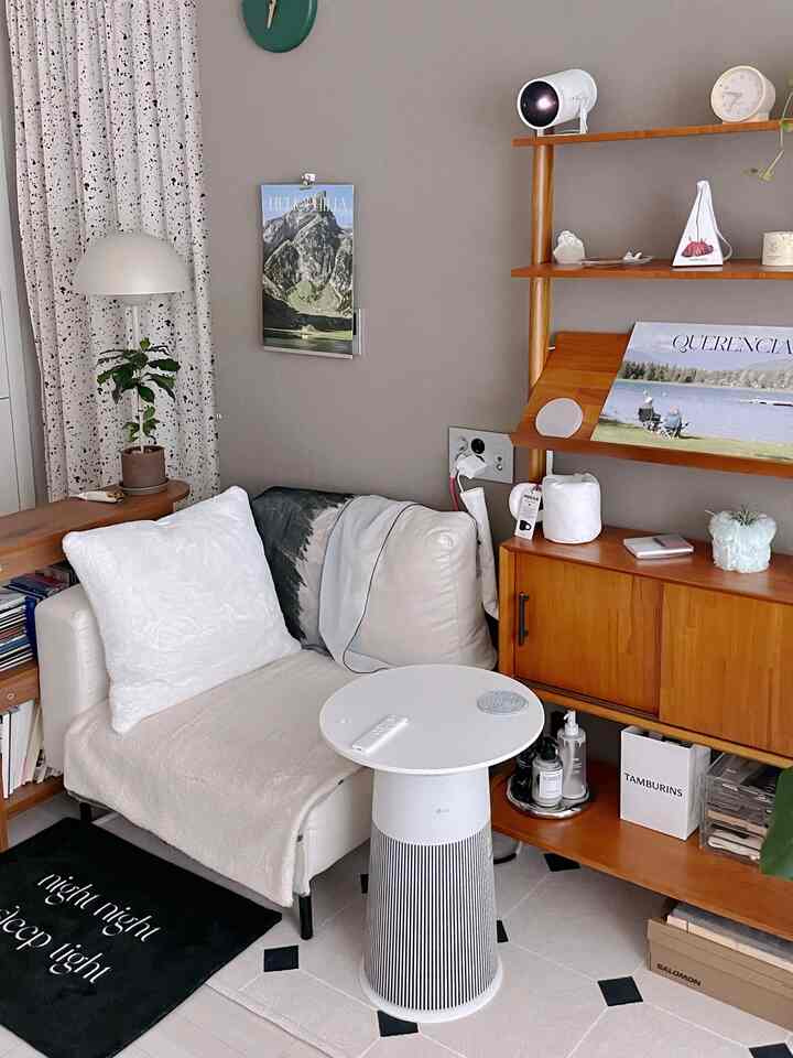 アイボリーとブラウンのトーンのリビング、居心地の良いアームチェアと木製キャビネット、整った小物が配置されたモダンな空間