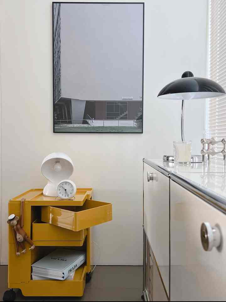 Living room interior with yellow rolling cart and modern table lamp against white wall