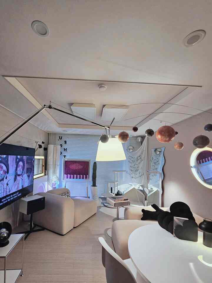 Minimal living room in white and beige tones featuring a solar system mobile and cat house with cozy atmosphere