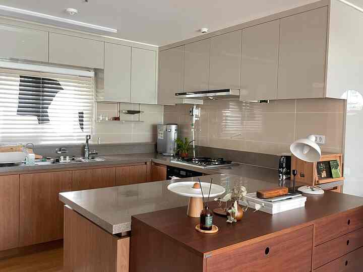 A modern kitchen featuring bright white and wood tones, spacious cabinetry and clean cooking area creating a neat atmosphere