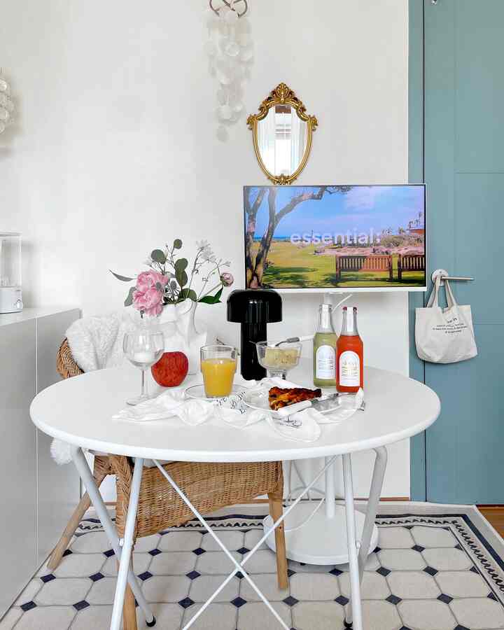 Cozy kitchen-dining space in white and wood tones featuring a round table with drinks and modern decor elements