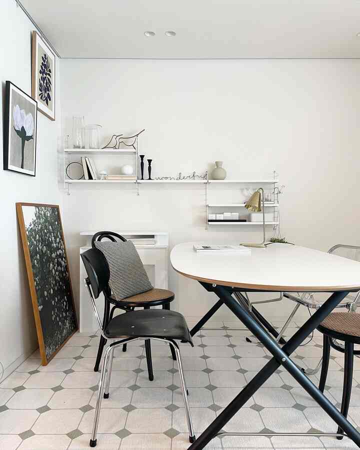 Minimal modern dining area with white walls, a white dining table, and black chairs